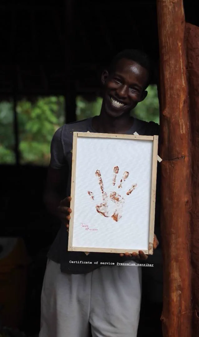 A smiling Earth House participant holding a handprint certificate
