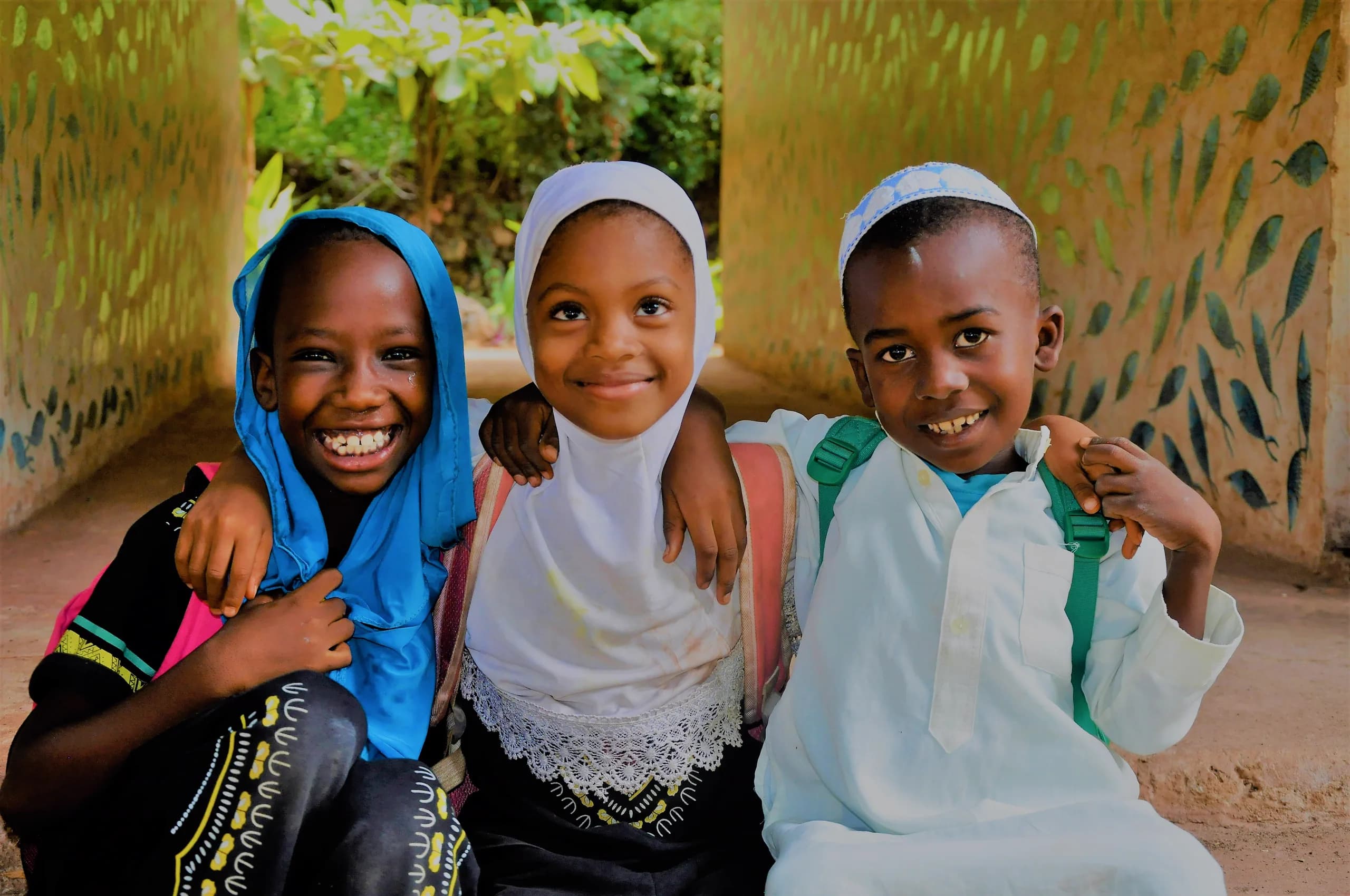 Three smiling young learners at Assalam