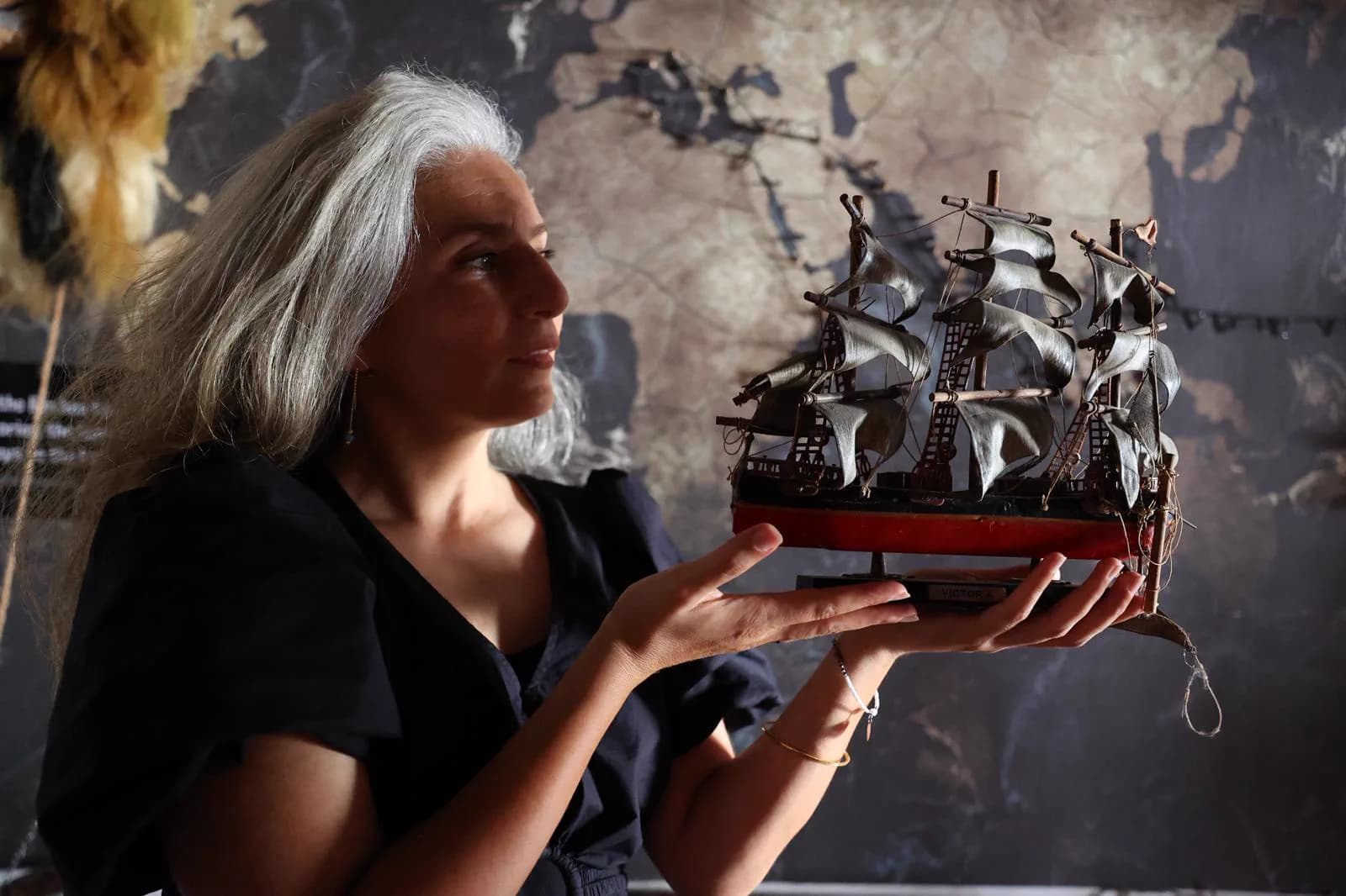 A visitor holding a model sailing ship inside the Spice Route Museum
