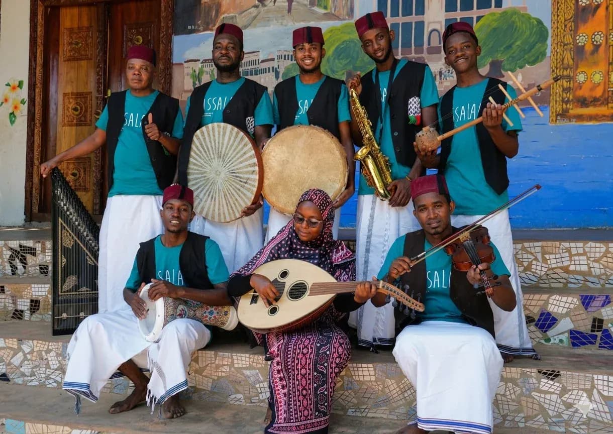 Eight Sawa Ensemble musicians posing together with oud, violin, saxophone and percussion instruments