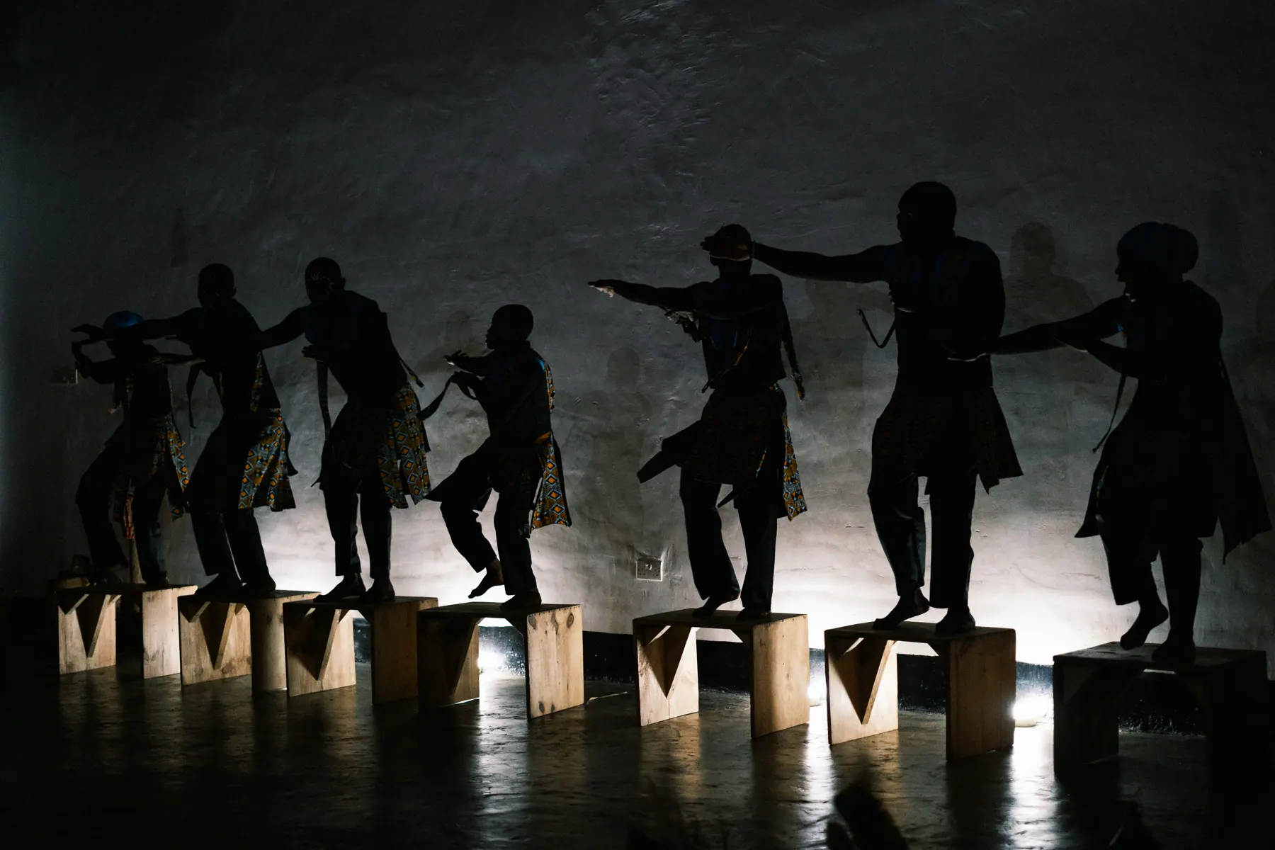 Sawa Ensemble performers balancing on wooden platforms in silhouette