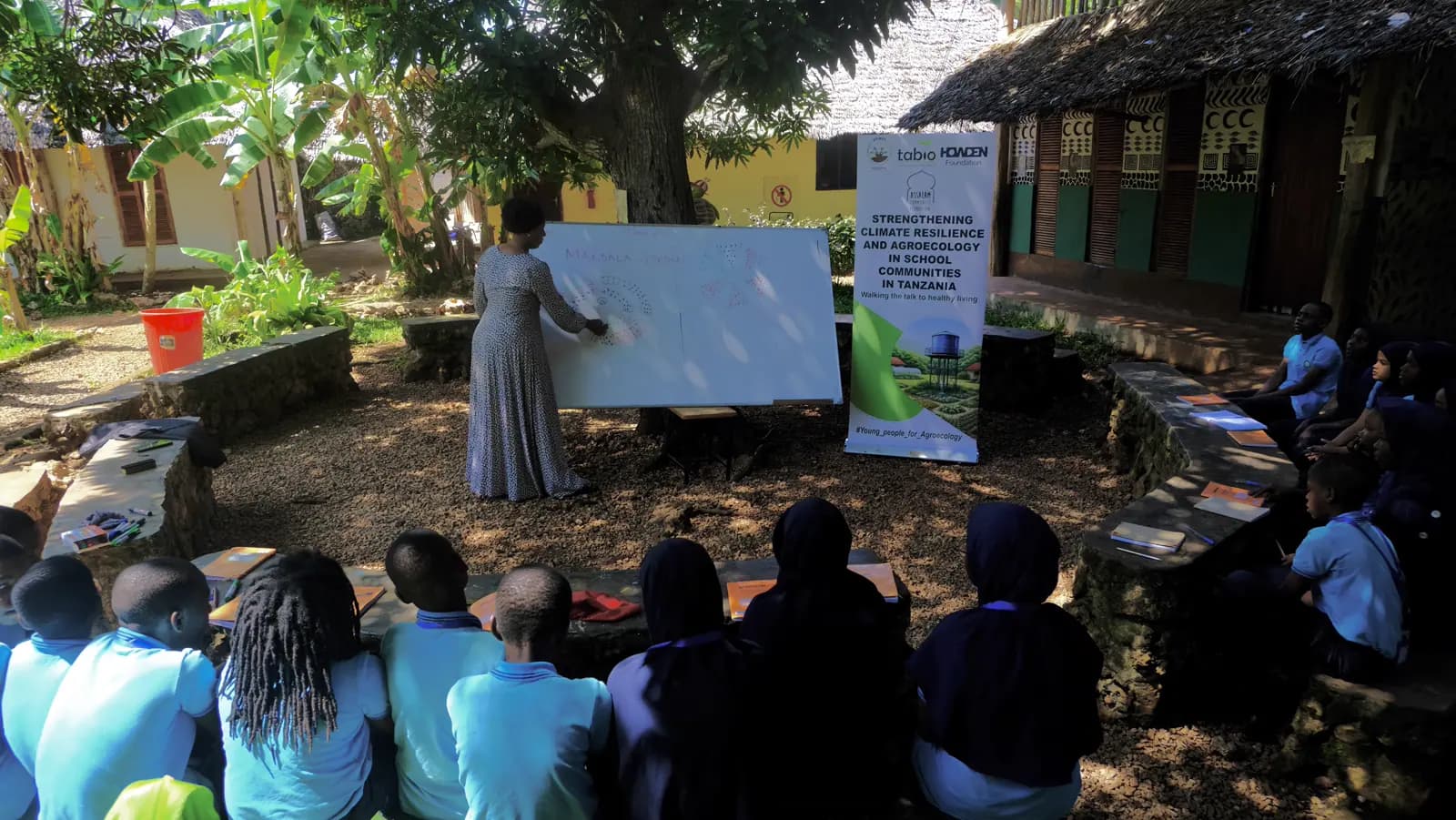Facilitator teaching students outdoors beside the school gardens