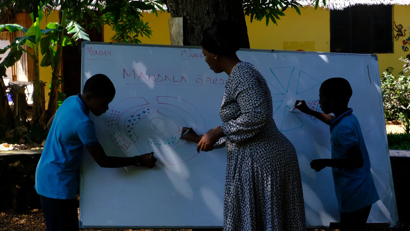 An educator and learners drawing a garden plan together at Assalam