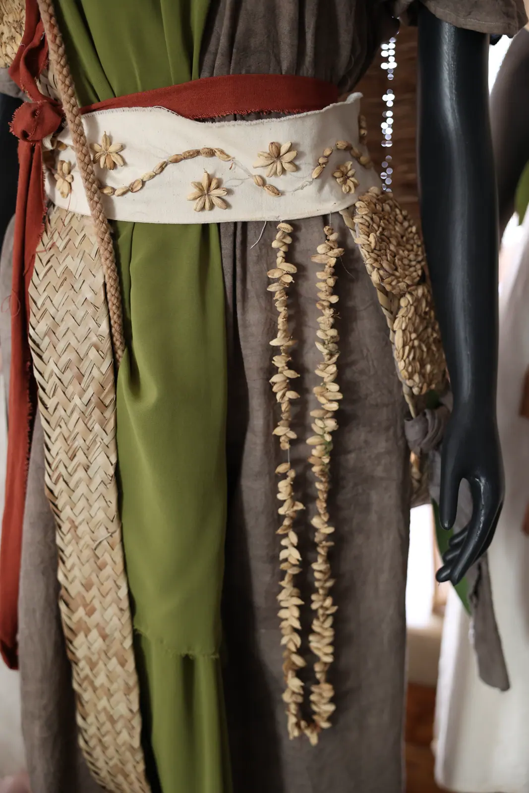 Person wearing a traditionally crafted woven belt and embroidered clothing